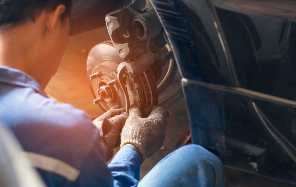 An image of an auto repair technician working on the breaks of a car.