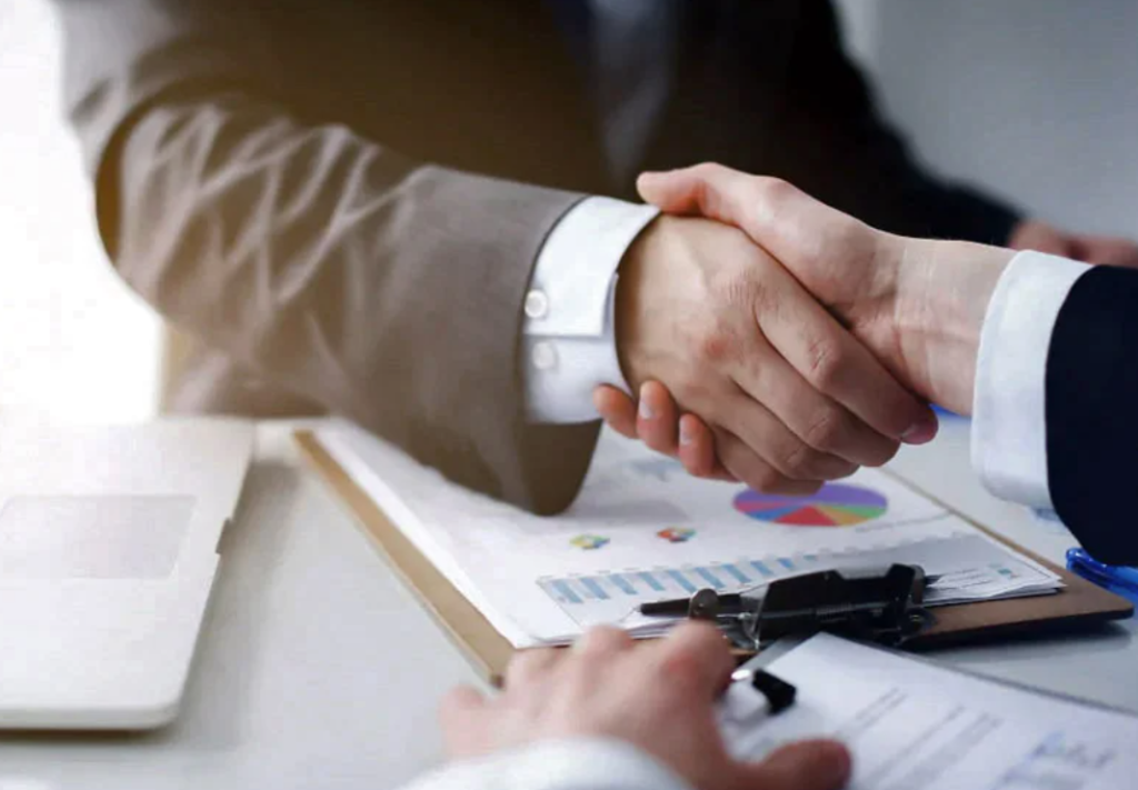 Two men shaking hands after a contract has been signed.