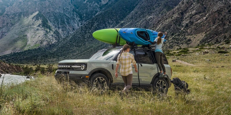 A 2024 Bronco Sport with a kayak strapped to the top and the owner entering the vehicle.