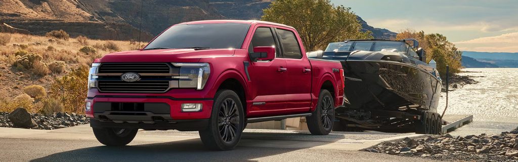 Ford F-150 pickup truck towing a boat near a scenic lakeside.