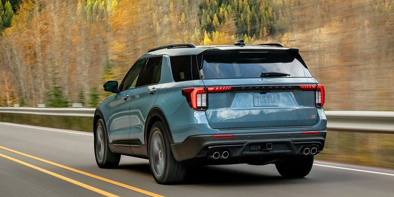 Blue SUV driving on a scenic road surrounded by autumn trees